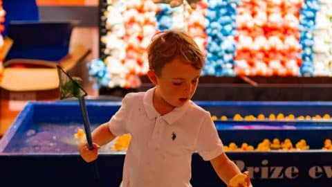 young boy playing a carnival game indoors