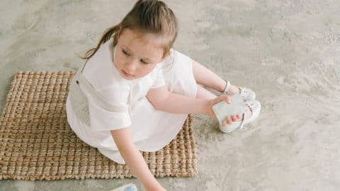 photograph of a kid sitting on the floor while holding cards